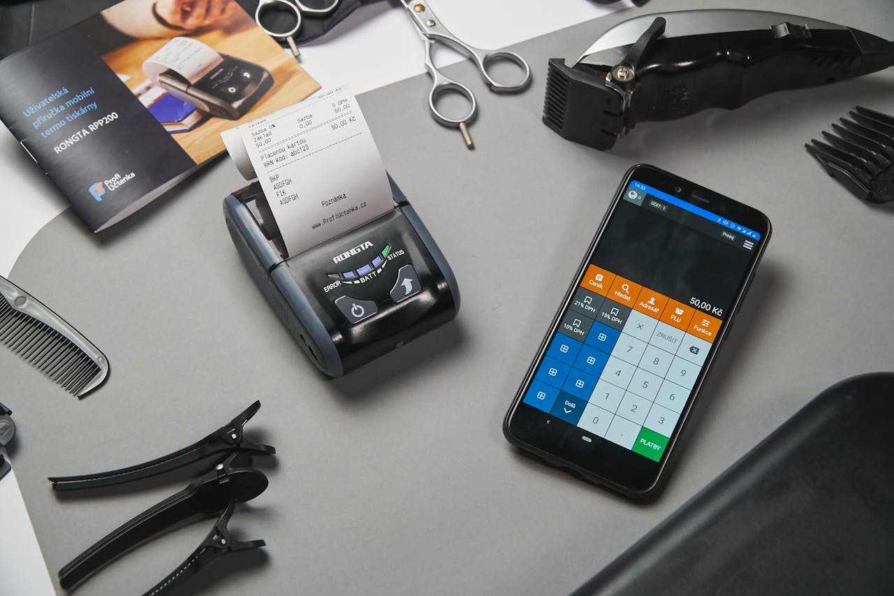 A mobile point-of-sale system in a barbershop featuring a smartphone and printer amidst salon tools.